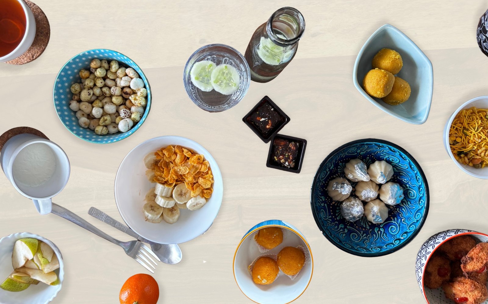 An overhead view of a festive food spread representing mindful eating, featuring a balance of Indian sweets like laddoos and modaks with healthy options like makhana, fruit, and infused water