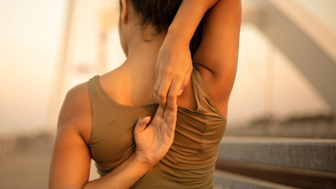 Person stretching arms behind their back outdoors during golden hour